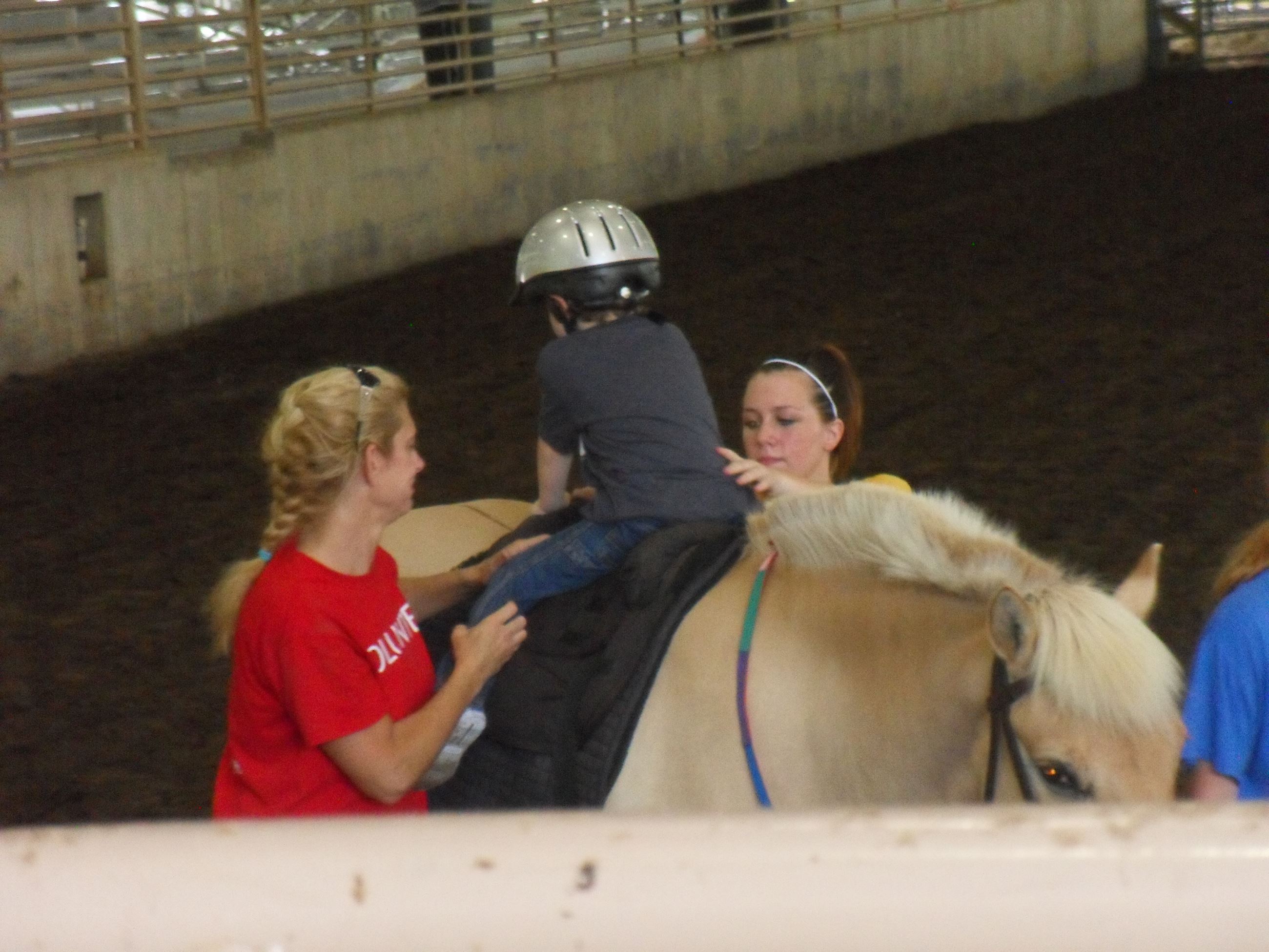 Women assisting child ride horse