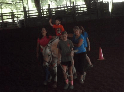 Child riding a horse and waving
