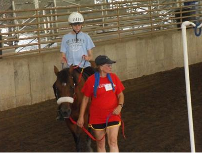 Child riding a horse being walked by a girl